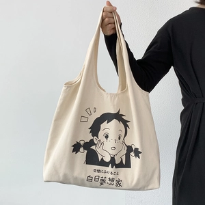 Détail d'un sac cabas en toile beige avec illustration de dessin animé et texte noir