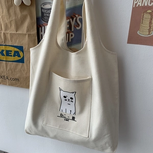 Detail of minimalist cream canvas tote bag featuring cute black cat print and outer pocket