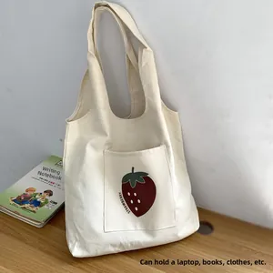 Detail of minimalist cream canvas tote bag featuring a strawberry print and large front pocket