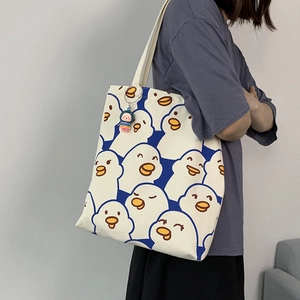 Detail view of large canvas tote bag with cartoon duck prints and plush pendant charm