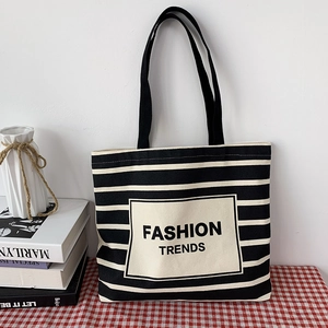 Close-up of black and white striped canvas tote bag with a Fashion Trends fabric patch