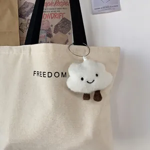 Minimalist canvas tote bag with FREEDOM print and cute cloud pendant in a lifestyle setting