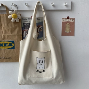 Detail shot of a minimalist cream canvas tote bag featuring a cute cat illustration