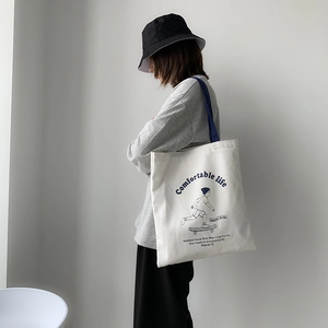 Detail of thickened white canvas tote bag with navy blue handles and skater illustration