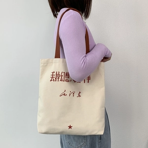 Detail of canvas tote bag with brown straps and red artistic calligraphy print