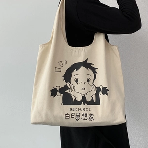 Détail d'un sac cabas en toile avec illustration d'anime noire porté à l'épaule