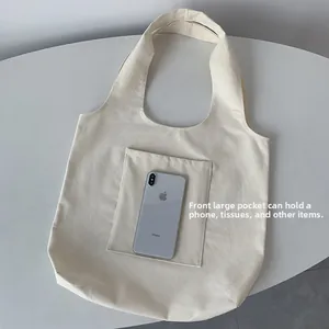 Detail shot of canvas tote bag featuring a large front pocket for phone and essentials