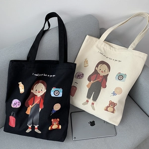 Close-up of black and beige canvas tote bags with artistic illustration on a sofa