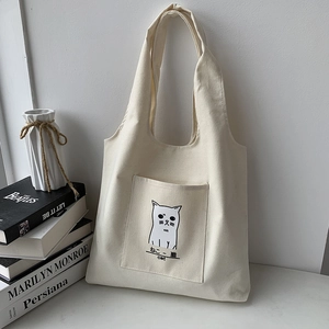 Detail of canvas tote bag featuring a front pocket and cute black cat illustration