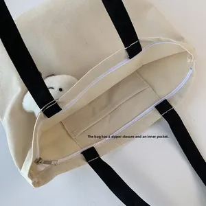 Detail of canvas tote bag showing zipper closure and internal pocket with white rabbit toy