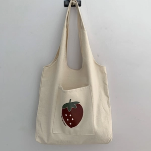 Detail of canvas tote bag featuring an outer pocket with a red strawberry print