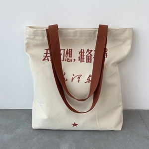 Detail of canvas tote bag with red slogan print and durable brown woven handles