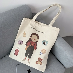 Detail of cream canvas tote bag featuring cute cartoon girl and travel illustrations