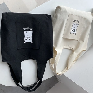 Detail of canvas tote bags showing outer pockets with minimalist cat illustrations