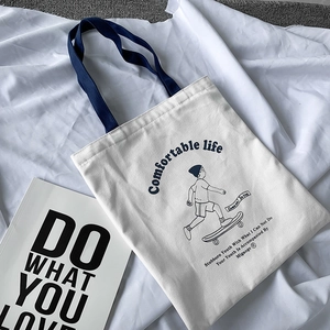Close-up of thick beige canvas tote with navy straps and skateboard boy illustration