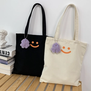 Minimalist canvas tote bags in black and beige featuring orange smiley and purple plush charm