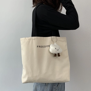 Minimalist beige canvas tote bag with black strap and freedom print for women