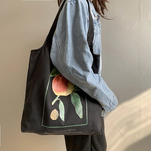 Détail du sac fourre-tout en toile noire avec imprimé botanique pêche et citation
