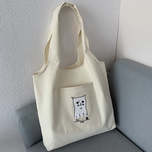 Close-up of the front pocket on the cream canvas tote featuring a cute cartoon cat print