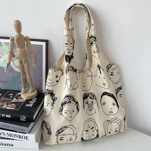 Detail shot of canvas tote bag featuring minimalist line art face illustrations