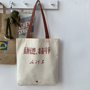 Detail view of canvas tote bag featuring red Chinese calligraphy and brown handle strap