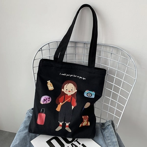 Detailed view of black canvas tote bag with cute cartoon girl and travel illustrations