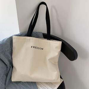 Detail view of large canvas tote bag with Freedom letters hanging on a chair