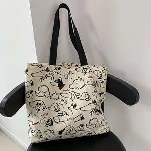 Minimalist canvas tote bag with artistic dog illustrations on a stylish black armchair