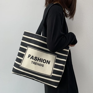 Minimalist black and white striped canvas tote bag worn on shoulder by a model