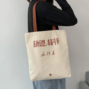 Detail of canvas tote bag with red calligraphy slogan and star on textured fabric
