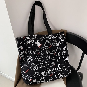 Close-up of black canvas tote bag with white dog illustrations and HOWL text detail