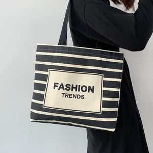 Detail of black and white striped canvas tote bag featuring Fashion Trends text logo