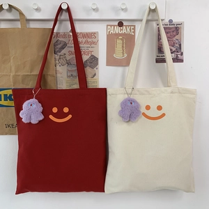 Simple canvas tote bag with orange smiley face and plush pendant for students