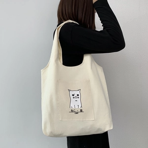 Detailed view of the cute cat illustration on a creamy white canvas shoulder tote bag