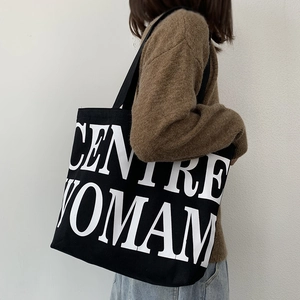 Detail view of large white letter print on a heavy duty black canvas tote bag