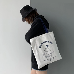 Detail of white canvas tote bag featuring blue skateboard graphic and zip closure