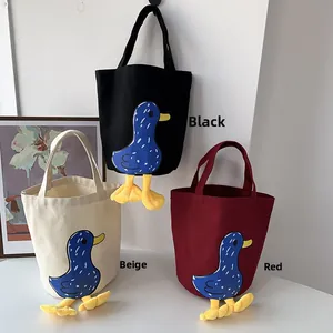 Close-up of canvas lunch bags with cartoon duck patterns and 3D feet decorations