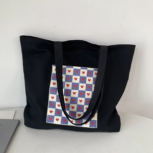 Detail view of black canvas tote bag with blue checkerboard pocket and red hearts
