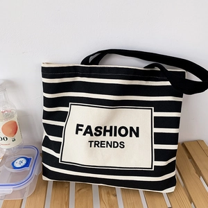Detail view of the black and white striped canvas tote bag on a wooden bench