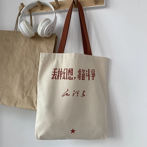 Detail of canvas tote bag with red strap, star motif, and elegant cursive text design