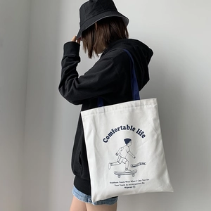 Detail of white canvas tote bag featuring blue handles and a skater cartoon print