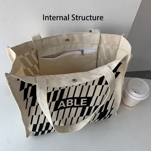 Beige canvas tote bag with ABLE print and geometric pattern showing internal pocket