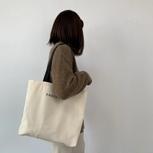 Detail view of large canvas tote bag with Freedom print and black shoulder straps