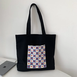 Detail of black canvas tote bag with purple checkered heart pocket and long handles