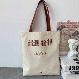 Detail of cream canvas tote bag with red slogan, star and brown woven strap