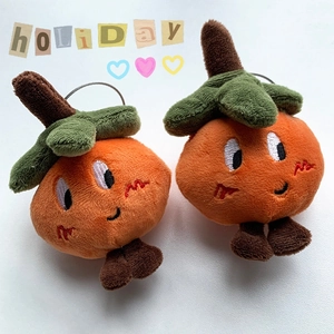Macro detail of pair cute orange plush pendants with embroidered faces and holiday text