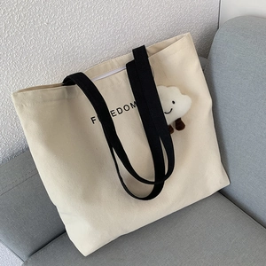 Detail of off-white canvas tote bag with black FREEDOM lettering and cloud pendant
