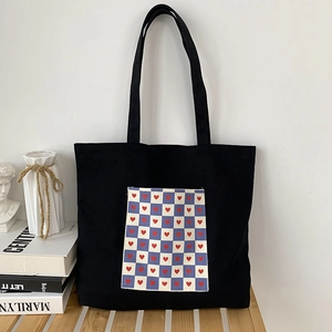 Detail of black canvas tote bag featuring a checkerboard pocket with red heart prints
