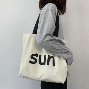 Detail of canvas tote bag featuring black sun print and durable shoulder strap