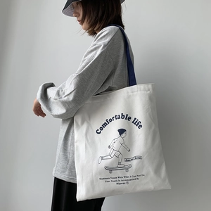 Detail of a white canvas tote bag with blue straps and artistic graphic print on a model